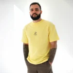 Чоловік у лимонній оверсайз-футболці Kyiv Digital «Як мене не любити» на повний зріст
